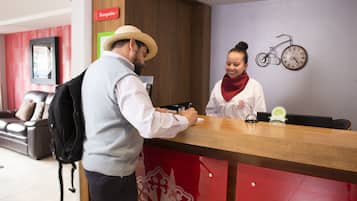 Een receptiebalie met een houten toonbank, een klok en een fiets aan de wand.
