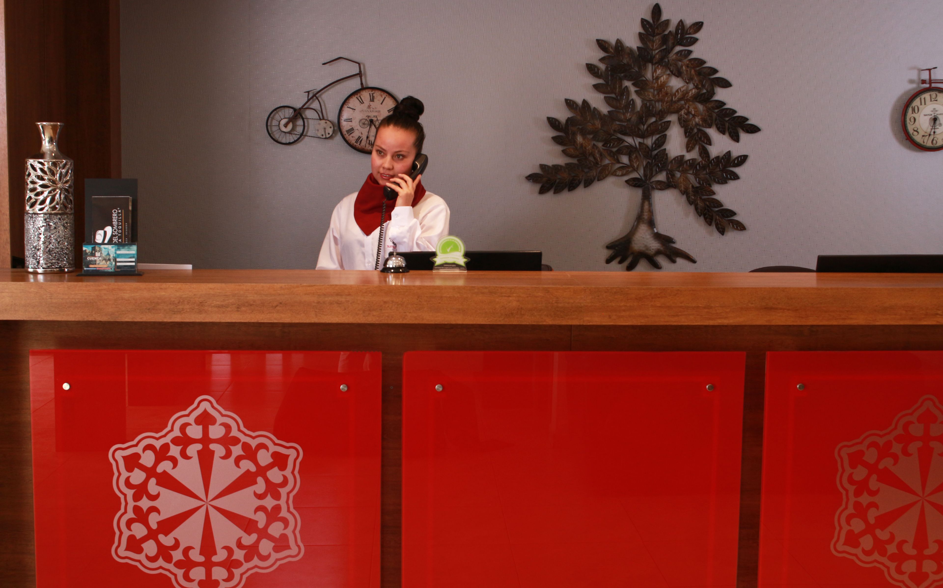 A reception desk with a clock, a decorative metal tree, and a vintage bicycle wall art.