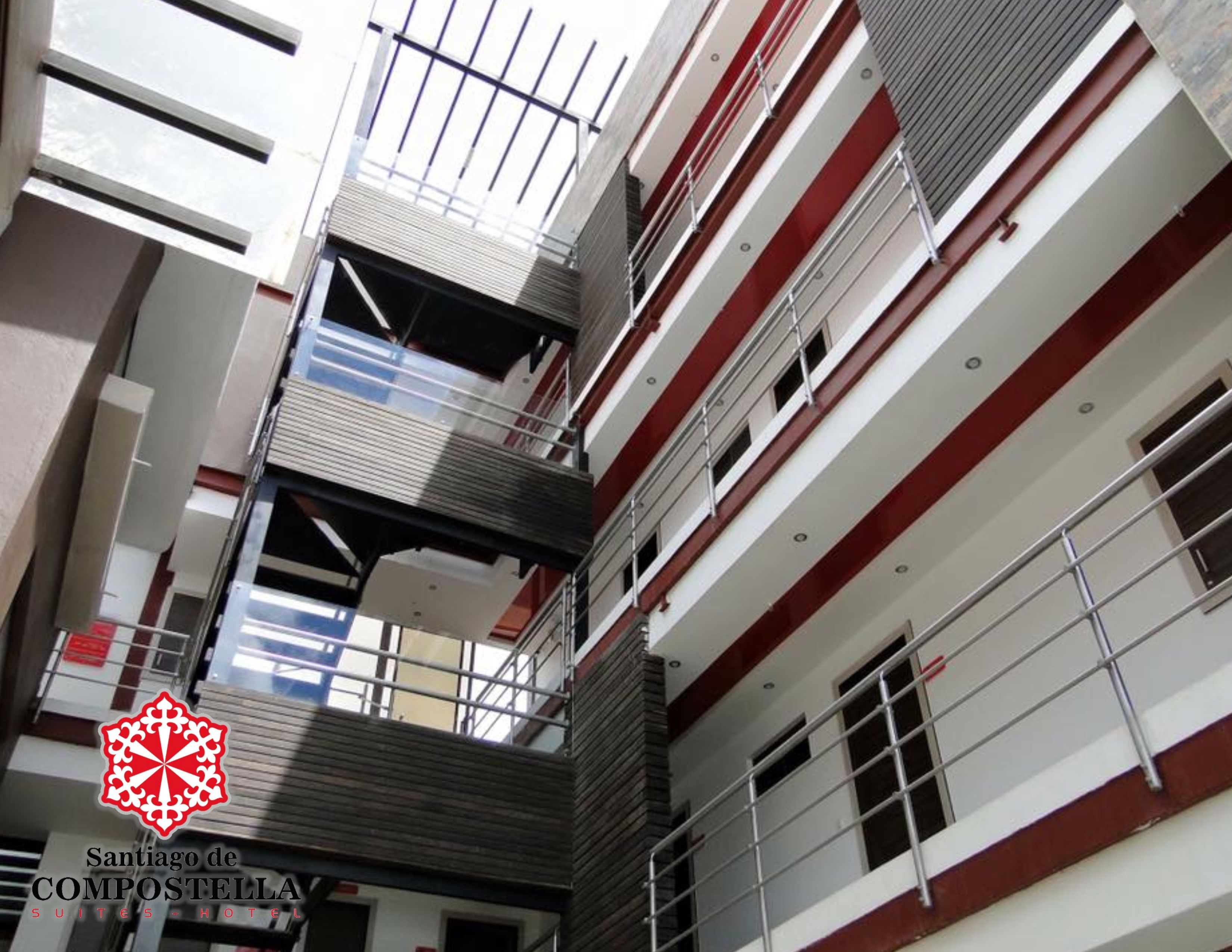 A multi-story building with balconies, a staircase, and a logo for Santiago de Compostela Suites Hotel.