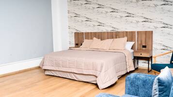 Une chambre à coucher avec un lit, une table de chevet, une chaise et un mur décoré d’un motif imitant le marbre.