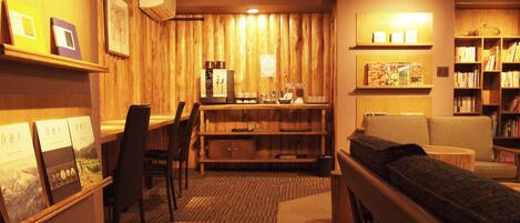 A cozy room with a wooden wall, a coffee machine, a bookshelf, and a sofa.