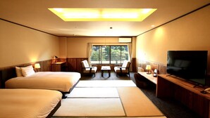 A hotel room with two beds, a desk, a TV, and a window with a view of trees. - Kutsurogijuku Chiyotaki (Aizuwakamatsu)