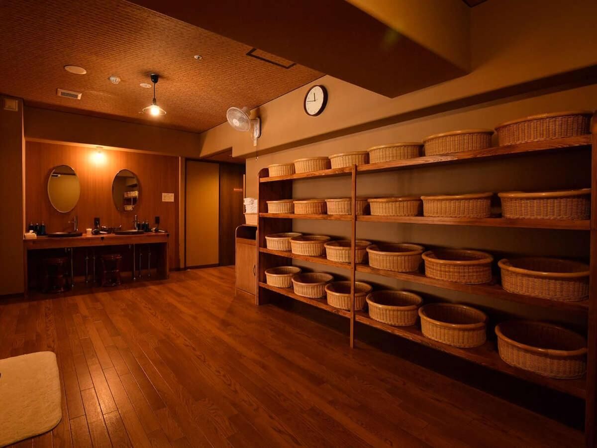 A room with wooden flooring, a reception desk, and shelves with baskets.