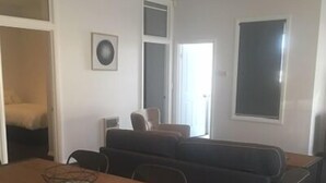 Un espacio habitable compacto con una mesa de comedor, un sofá y una pequeña cocina americana.