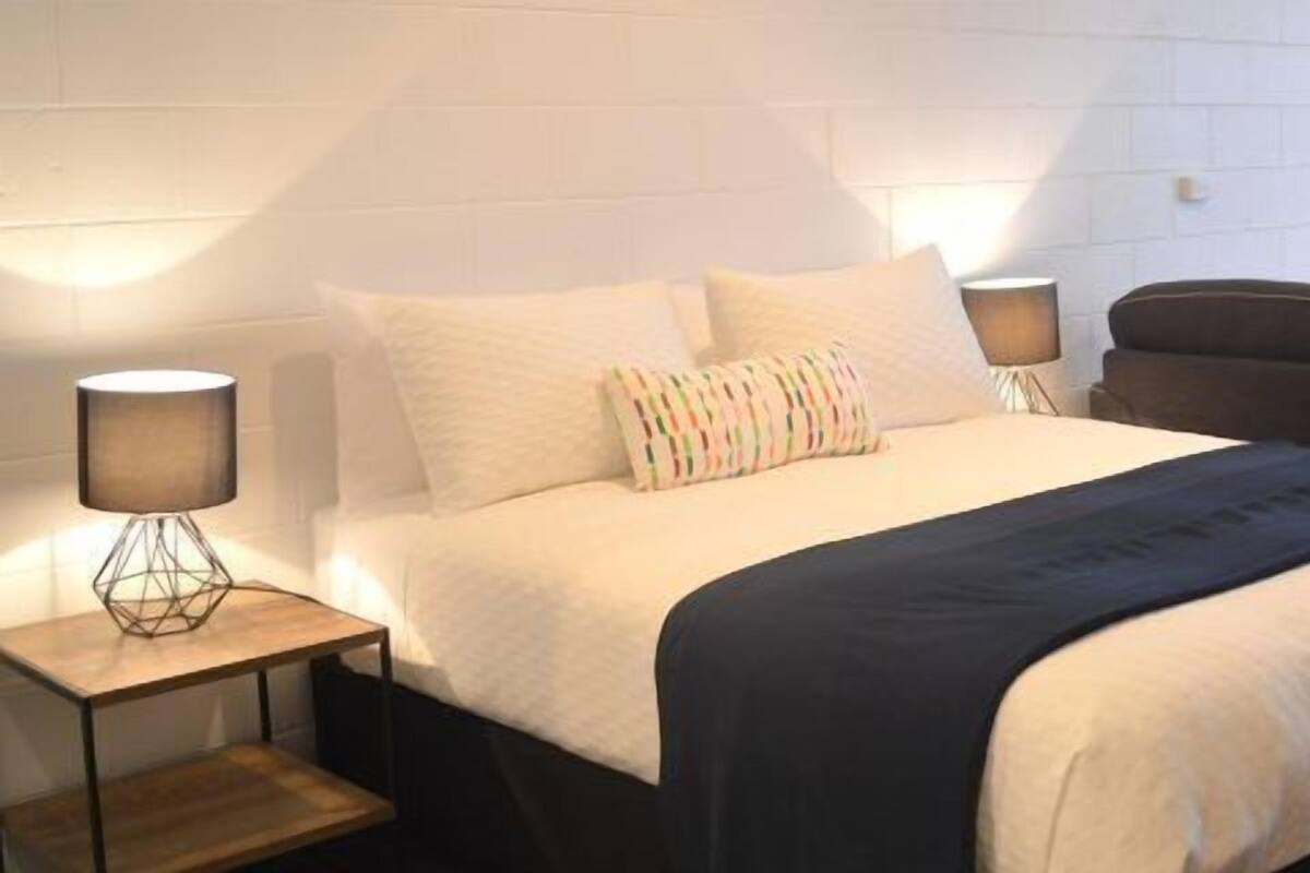Una habitación de hotel con una cama, un sofá, una silla, un televisor y una lámpara.