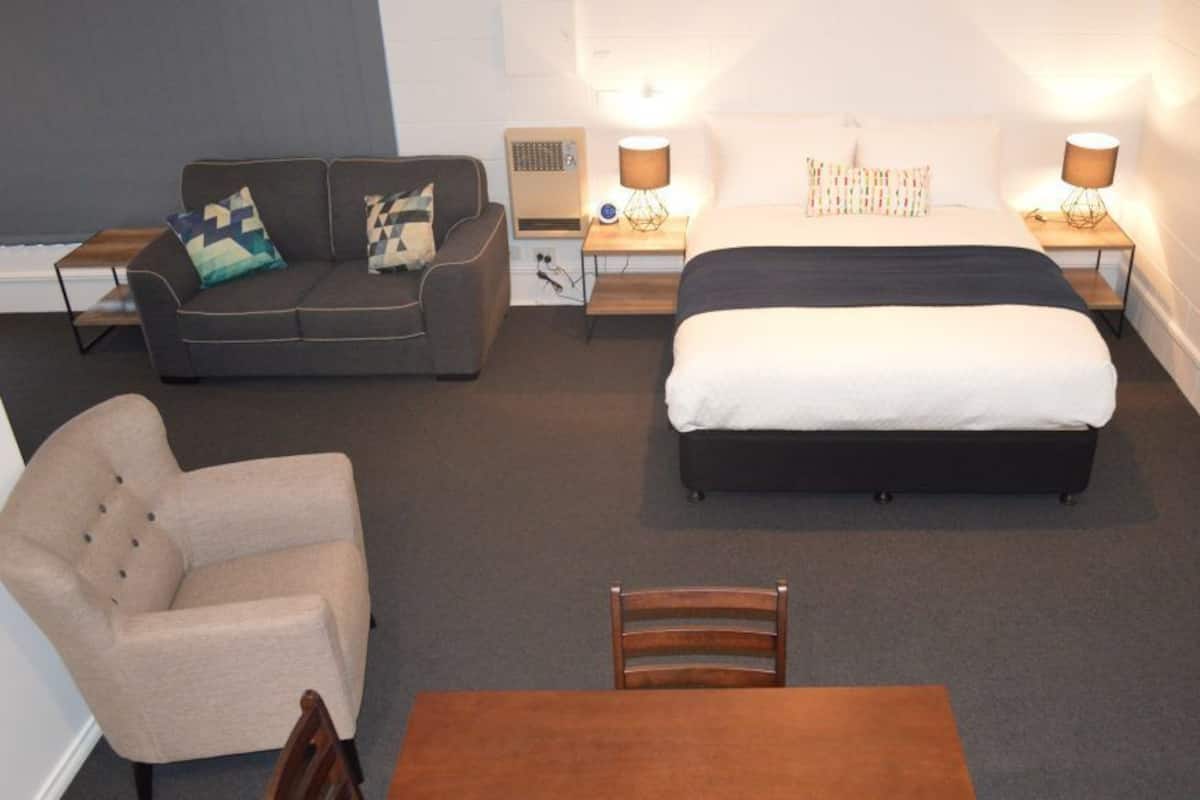 Una habitación de hotel con cama, sofá, silla y mesa.