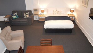 A hotel room with a bed, a sofa, a chair, and a table.