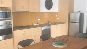 Cocina compacta con gabinetes de madera, microondas, estufa y refrigerador.