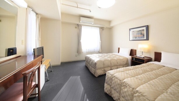 A hotel room with two beds, a desk, a chair, a television, an air conditioning unit, and a framed picture on the wall. - Shinjuku Urban Hotel (Tokyo)