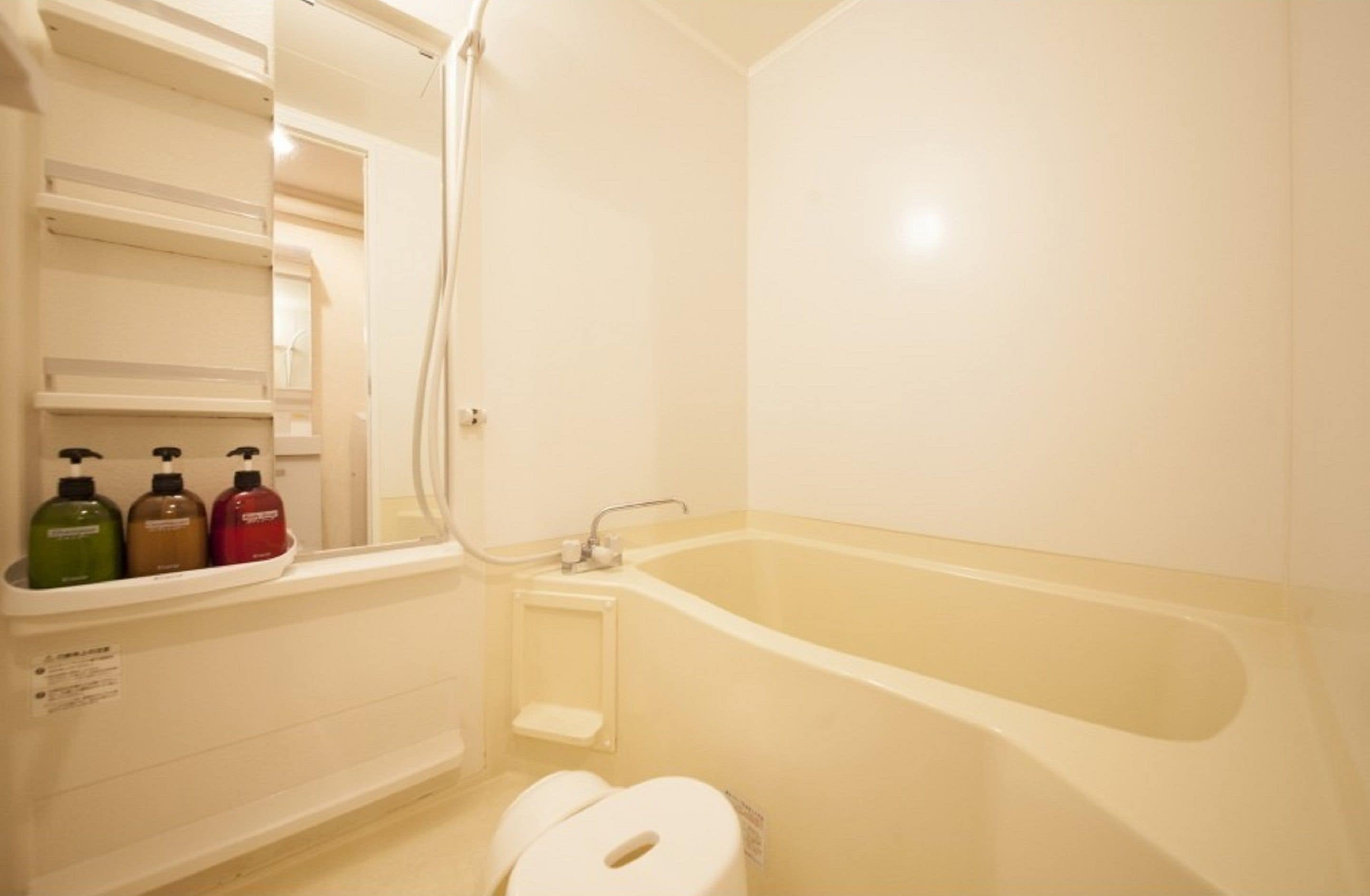 A bathroom with a bathtub, toilet, and shelves with toiletries.
