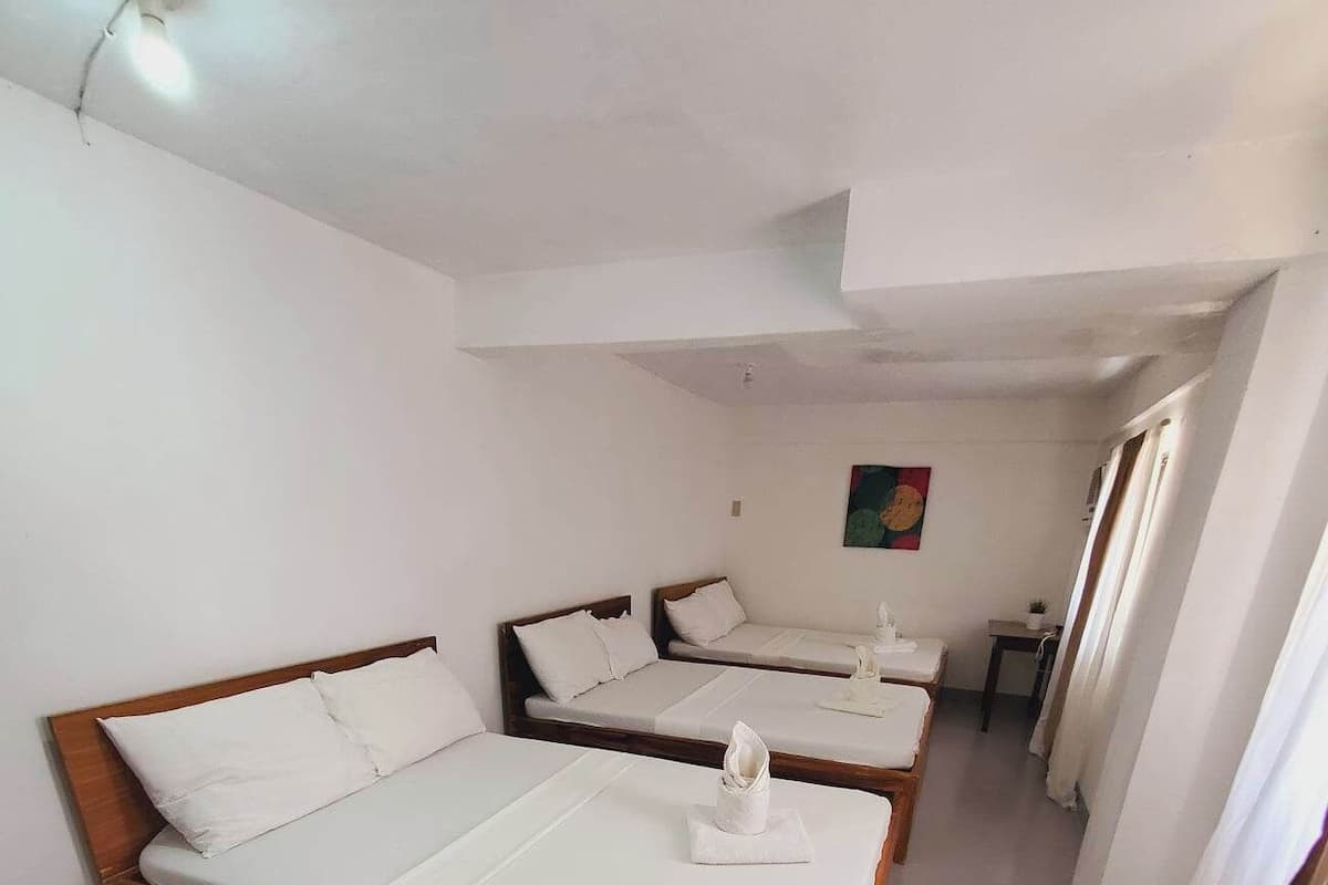 A hotel room with two single beds, a small table, and a painting on the wall.