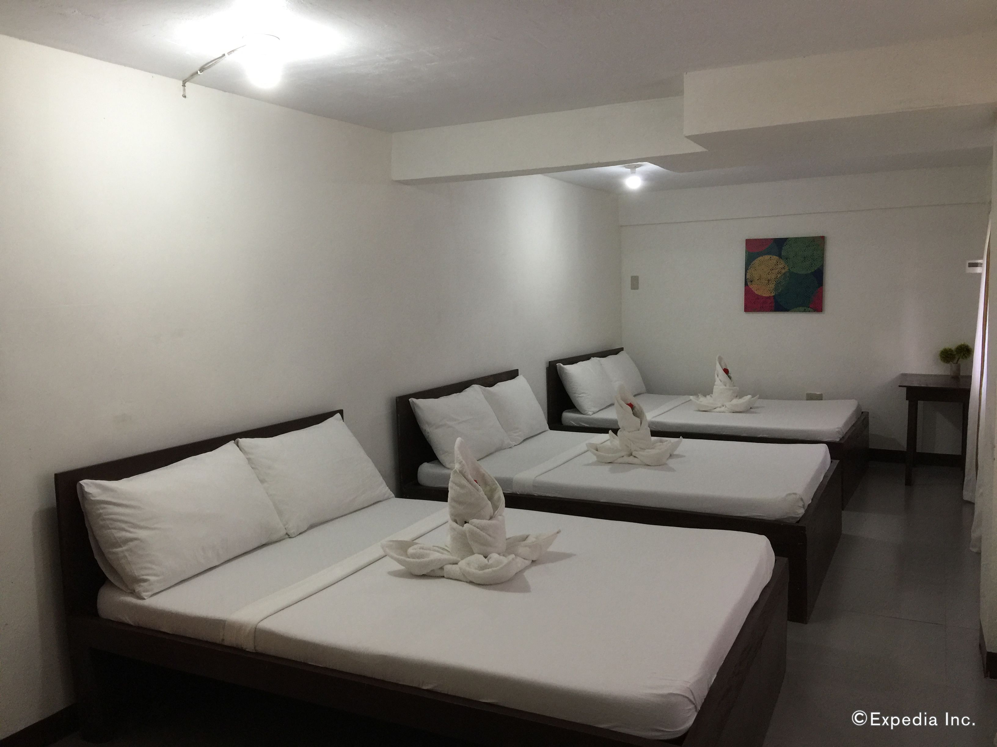 A hotel room with three single beds, each with white linens and decorative swans.