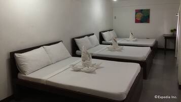 A hotel room with three single beds, each with white linens and decorative swans.