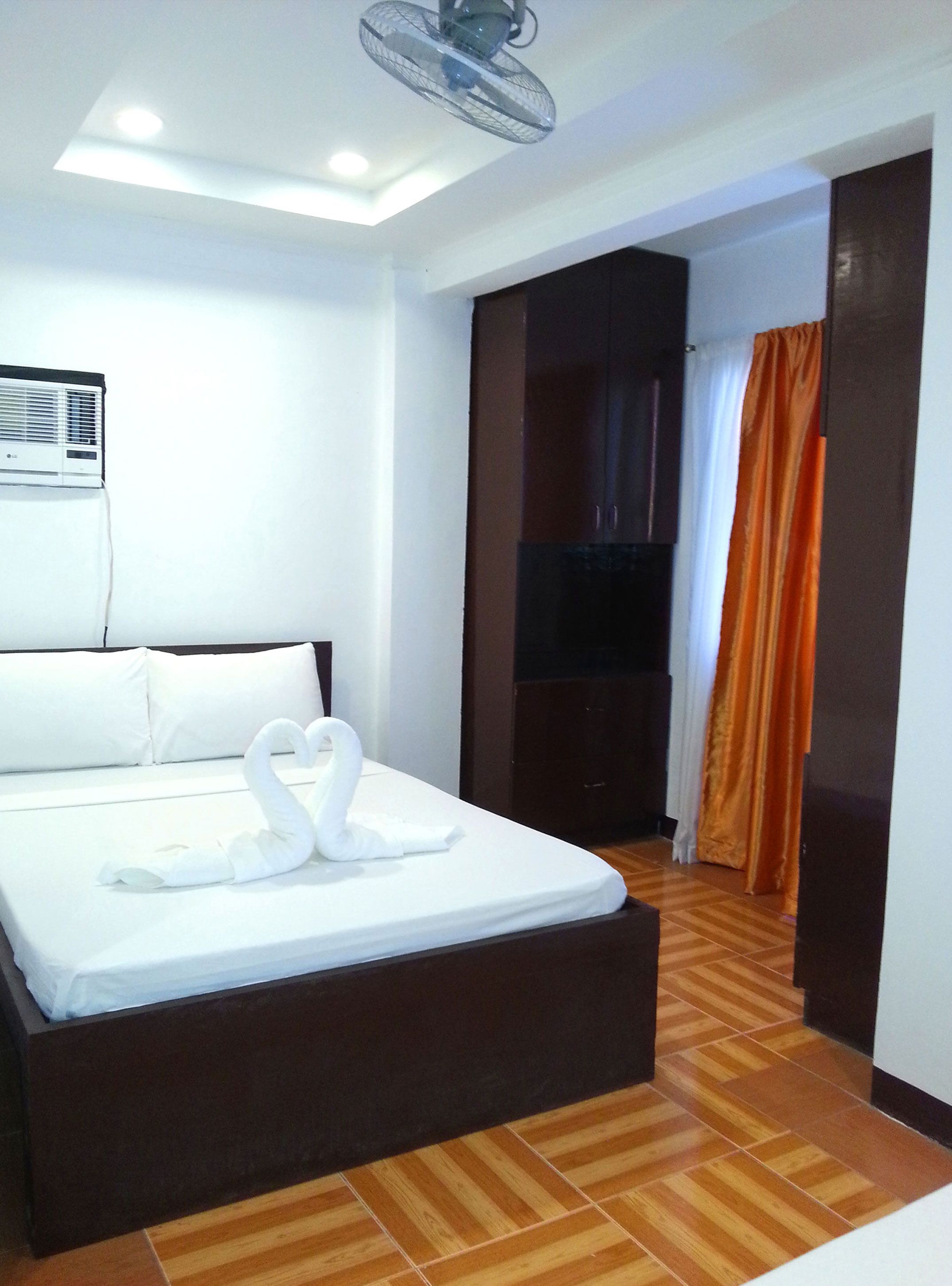 Une chambre d’hôtel équipée d’un lit, d’un ventilateur de plafond, d’un appareil de climatisation, d’un plancher en bois et d’une porte coulissante.