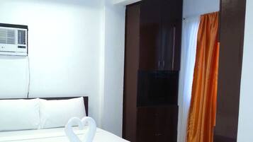 Une chambre d’hôtel équipée d’un lit, d’un ventilateur de plafond, d’un appareil de climatisation, d’un plancher en bois et d’une porte coulissante.