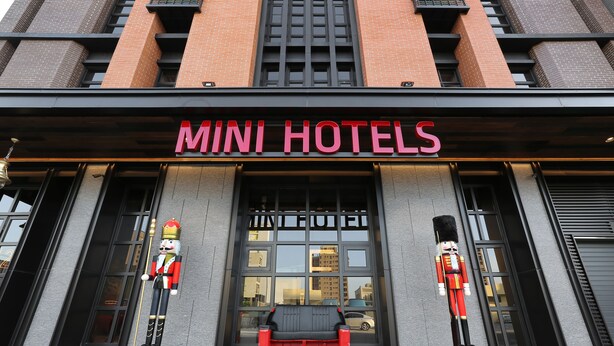The exterior of a building with a sign reading "MINI HOTELS" and two nutcracker statues. - Mini Hotels Feng Jia Branch (Taichung)