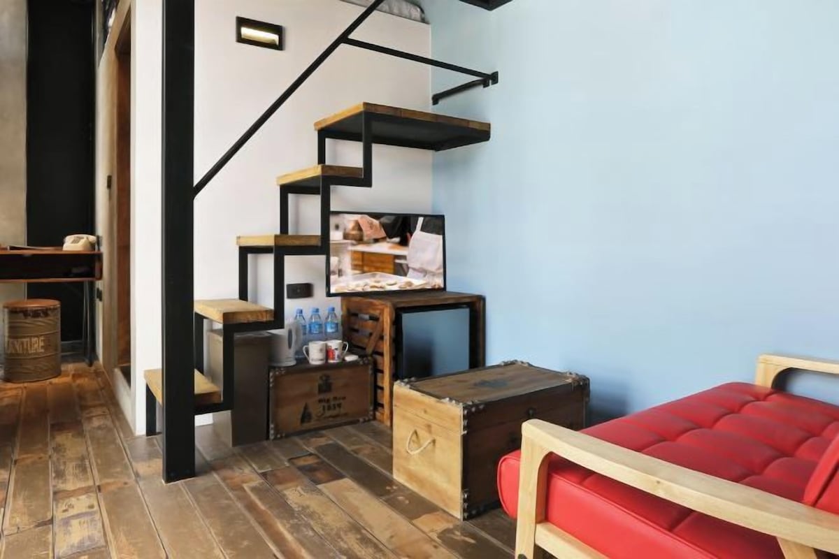 Une pièce avec un escalier, des meubles en bois et un canapé rouge.