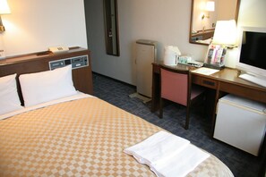 A hotel room with a bed, desk, chair, refrigerator, and a television.