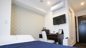 A hotel room with a bed, a desk with a computer, a chair, an air conditioning unit, a television, and a door. - HOTEL LiVEMAX Minamihashimoto Ekimae (Sagamihara)