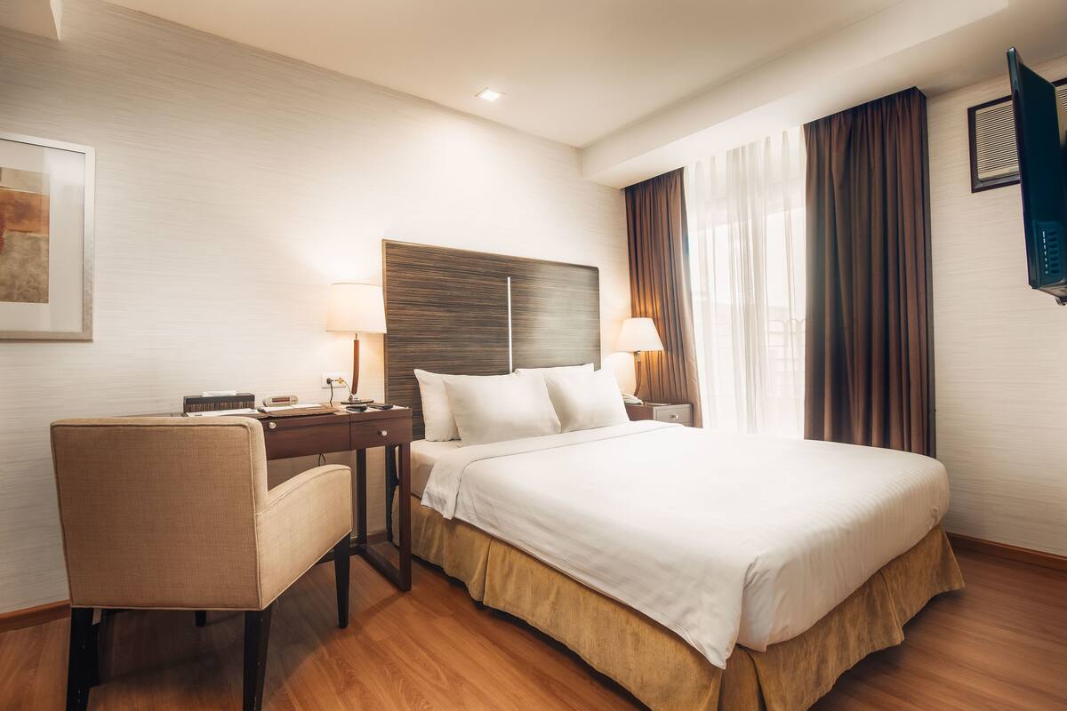 Una habitación de hotel con una cama, un escritorio, una silla y un televisor.