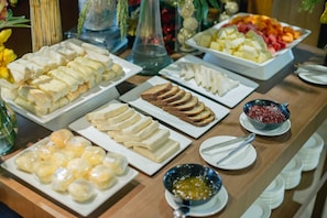 A buffet with various food items including sliced bread, cheese, and fruits. - The A. Venue Hotel (Makati)