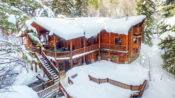 Una baita di legno con diversi livelli, balconi in legno e un paesaggio innevato.