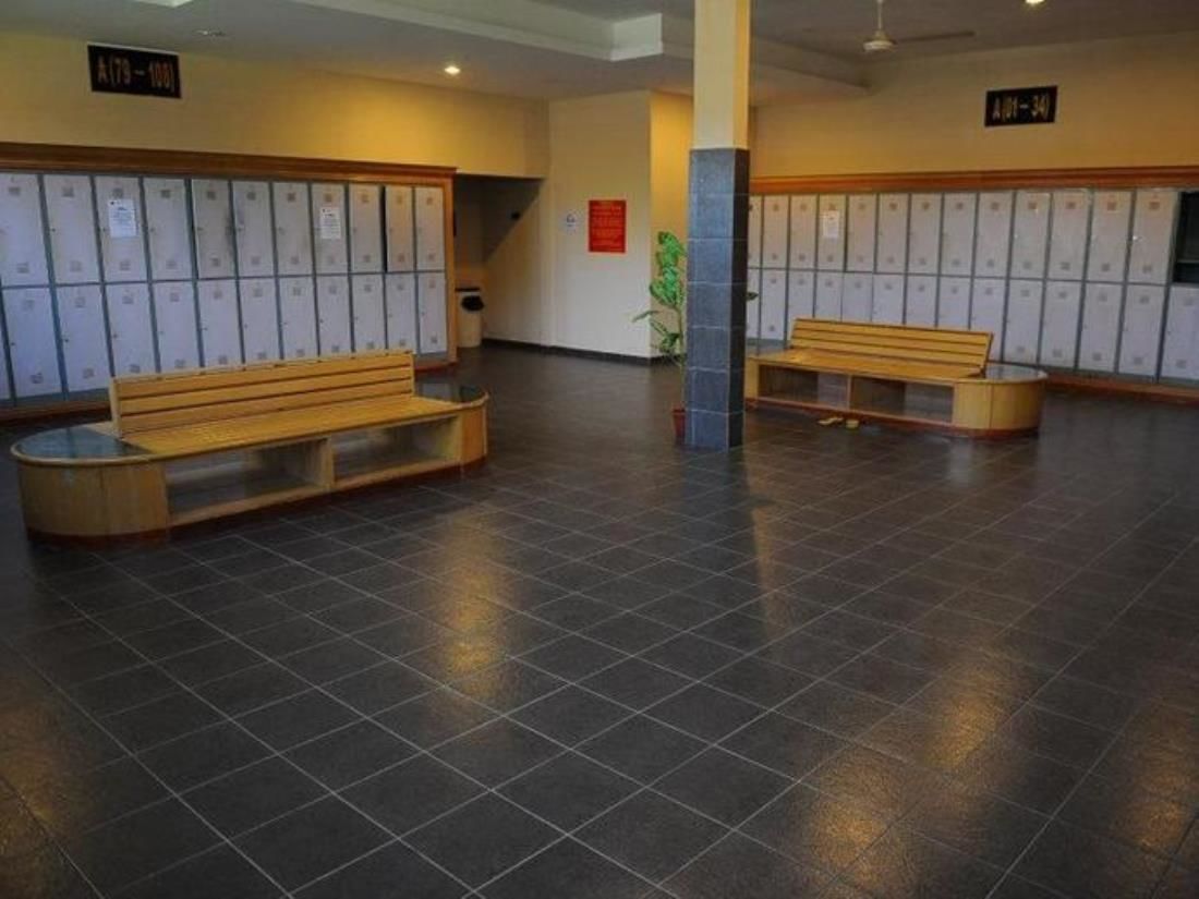 A lobby with two wooden benches, a tiled floor, and rows of lockers.