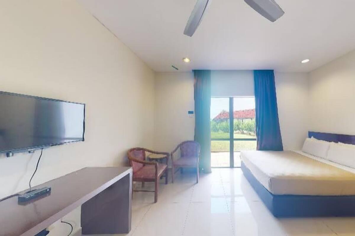 A hotel room with a bed, a TV, a desk, and a chair.