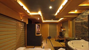 A modern hotel room with a bed, a desk, a large bathtub, and a bathroom with a marble wall. - Classic Hotel (Jakarta)