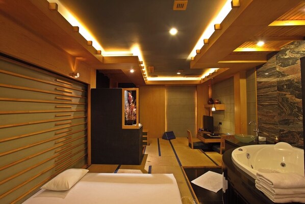 A modern hotel room with a bed, a desk, a large bathtub, and a bathroom with a marble wall. - Classic Hotel (Jakarta)
