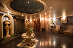 A lobby with a fountain, seating area, and a painting on the wall.