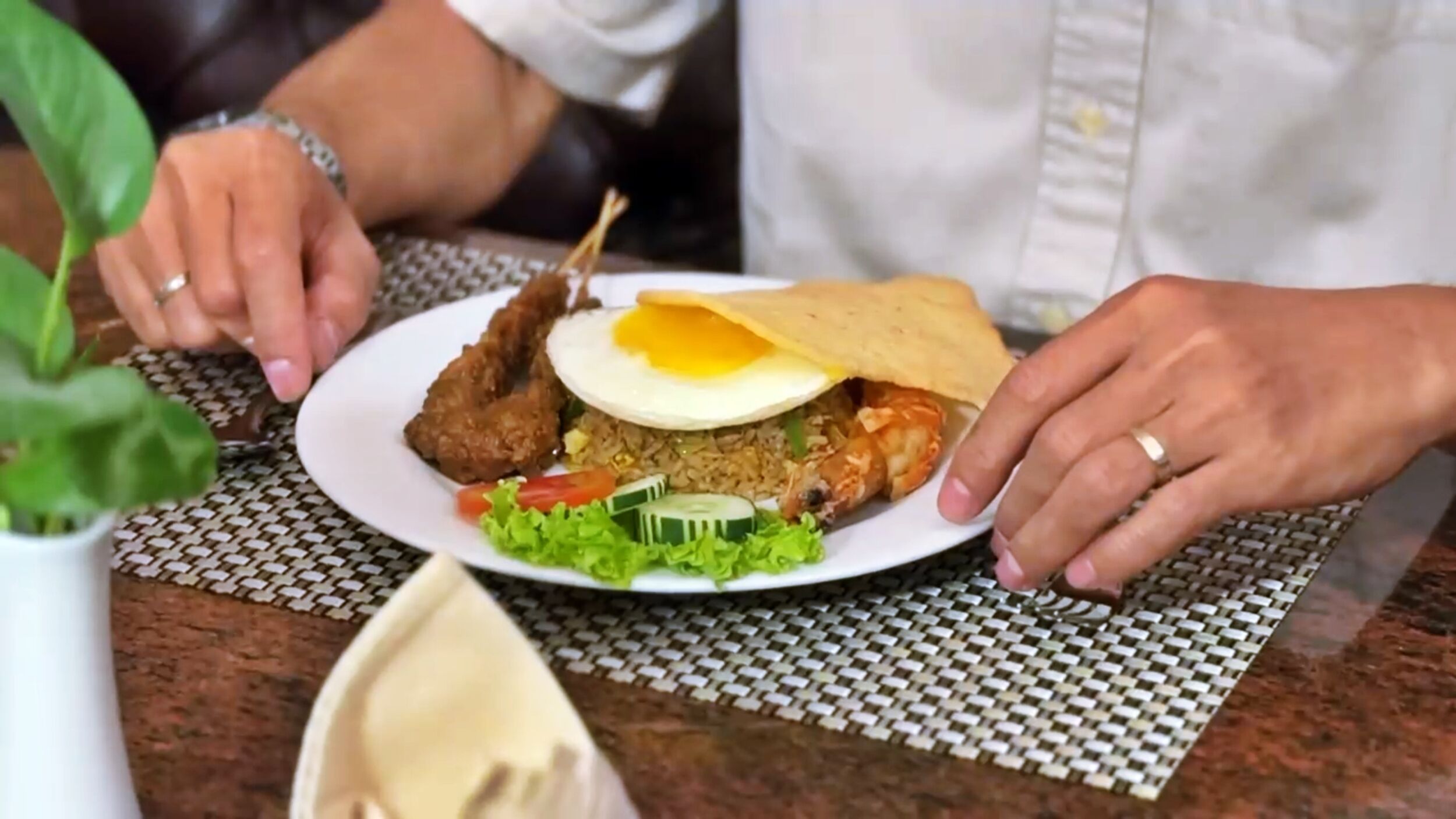 Un plato de comida con pollo frito, arroz, verduras y un huevo frito.