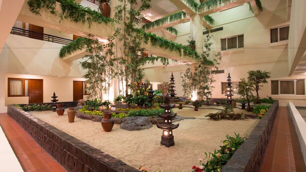 A multi-level indoor garden with potted plants, a sand garden, and traditional lanterns. - Classic Hotel (Jakarta)