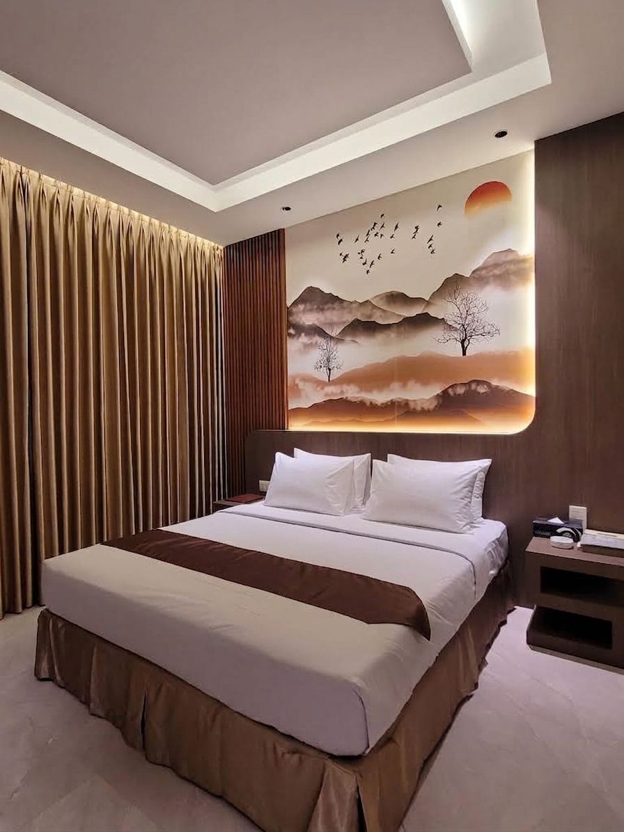 A modern hotel room with a large bed, a nightstand, and a wall mural depicting a landscape with birds.