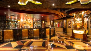 A bar area with a polished floor, bar counter, and various bottles and glasses. - Classic Hotel (Jakarta)