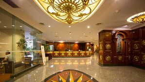 A hotel lobby with a reception desk, glass walls, and a decorative ceiling. - Classic Hotel (Jakarta)