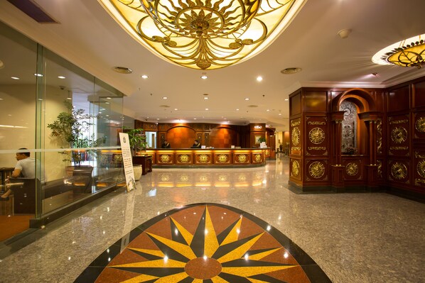 A hotel lobby with a reception desk, glass walls, and a decorative ceiling. - Classic Hotel (Jakarta)