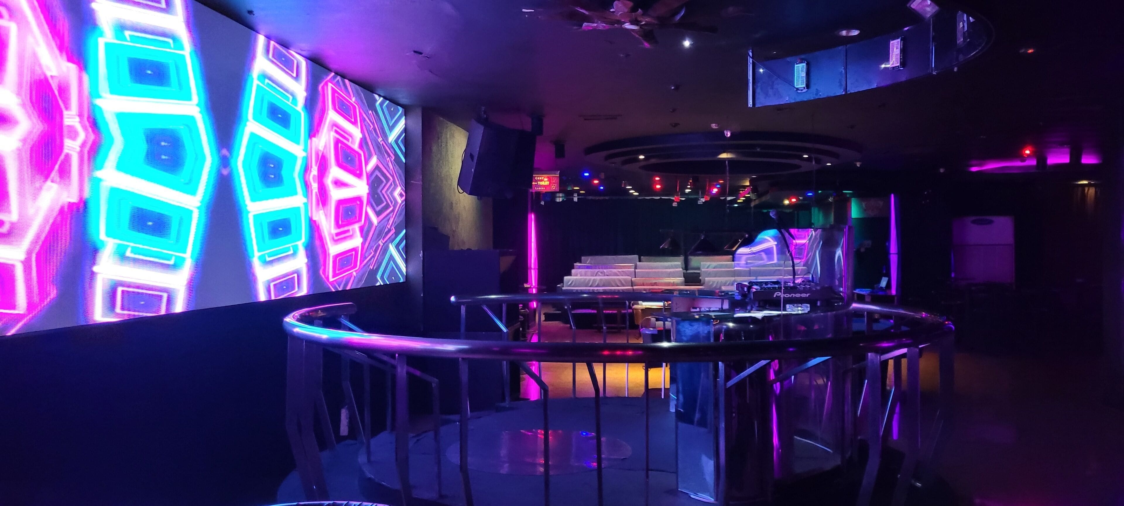 A modern interior with a curved railing, a stage area, and ambient lighting.