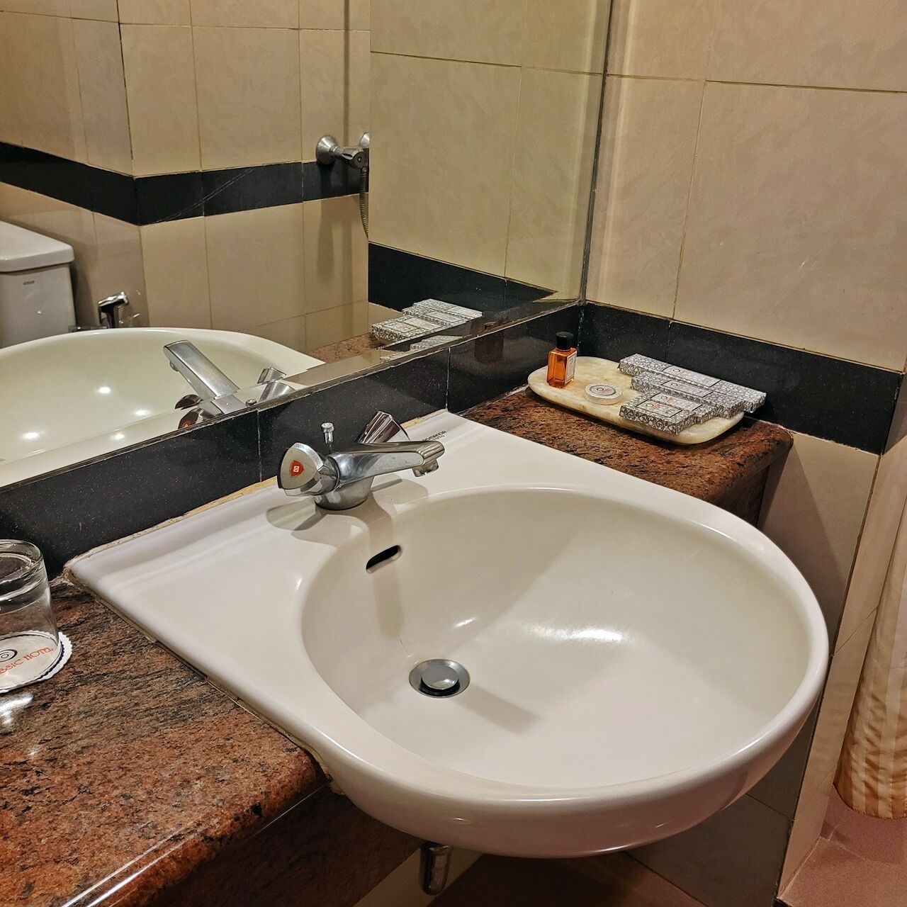 A bathroom with a white sink, a mirror, and a black countertop.