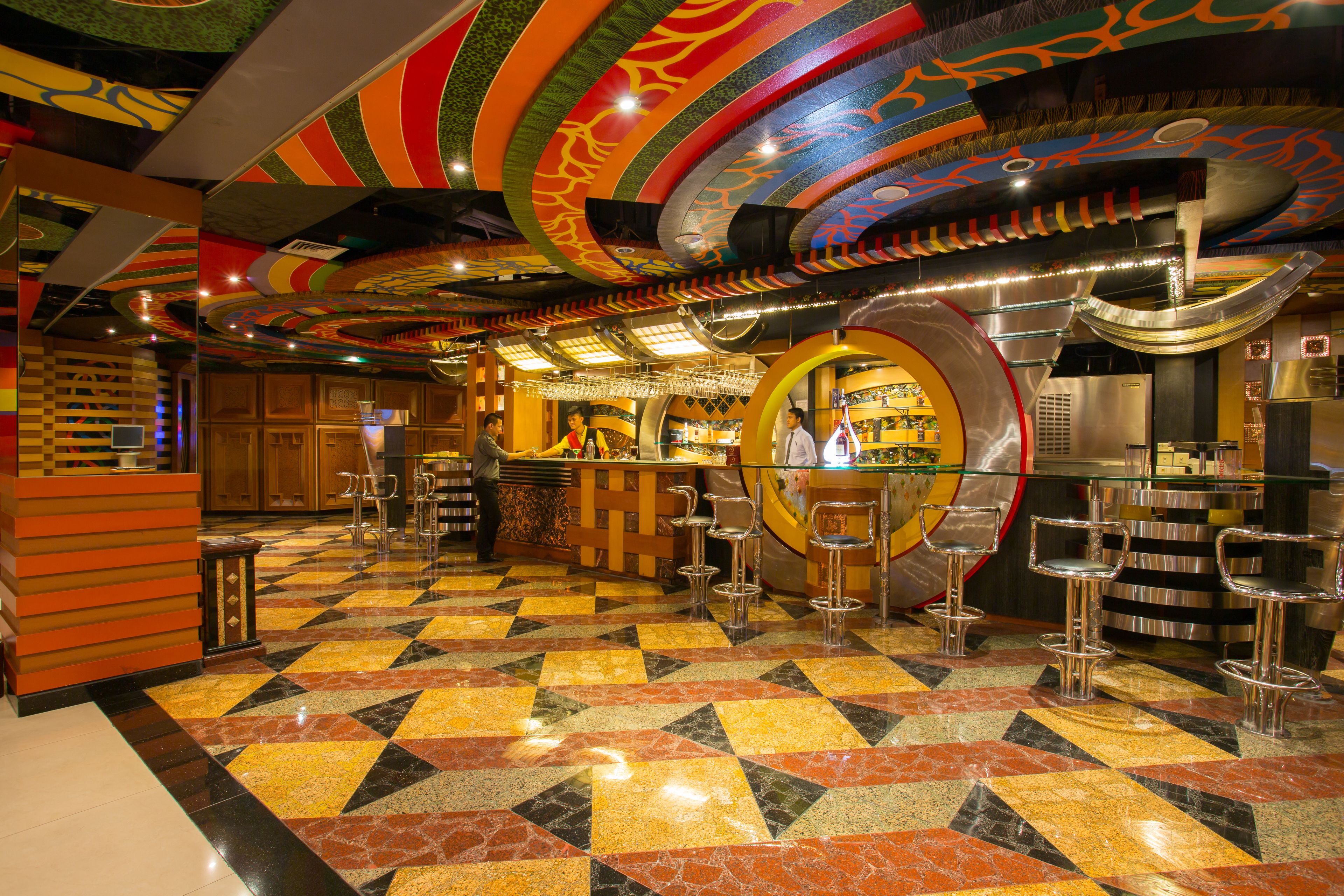 A bar area with a checkered floor, bar stools, and a circular bar counter.