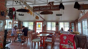 A restaurant with wooden tables and chairs, a sign reading "Scenic Riverside Resort," and a Christmas-themed tablecloth.