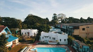 Zona residencial con casas blancas, piscina y abundante vegetación.