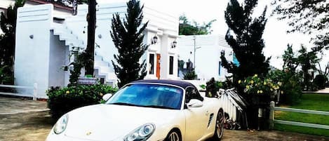 A white sports car parked in front of a white building with steps and a staircase.