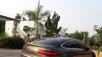 A parked car in front of a building with a white facade and a staircase.