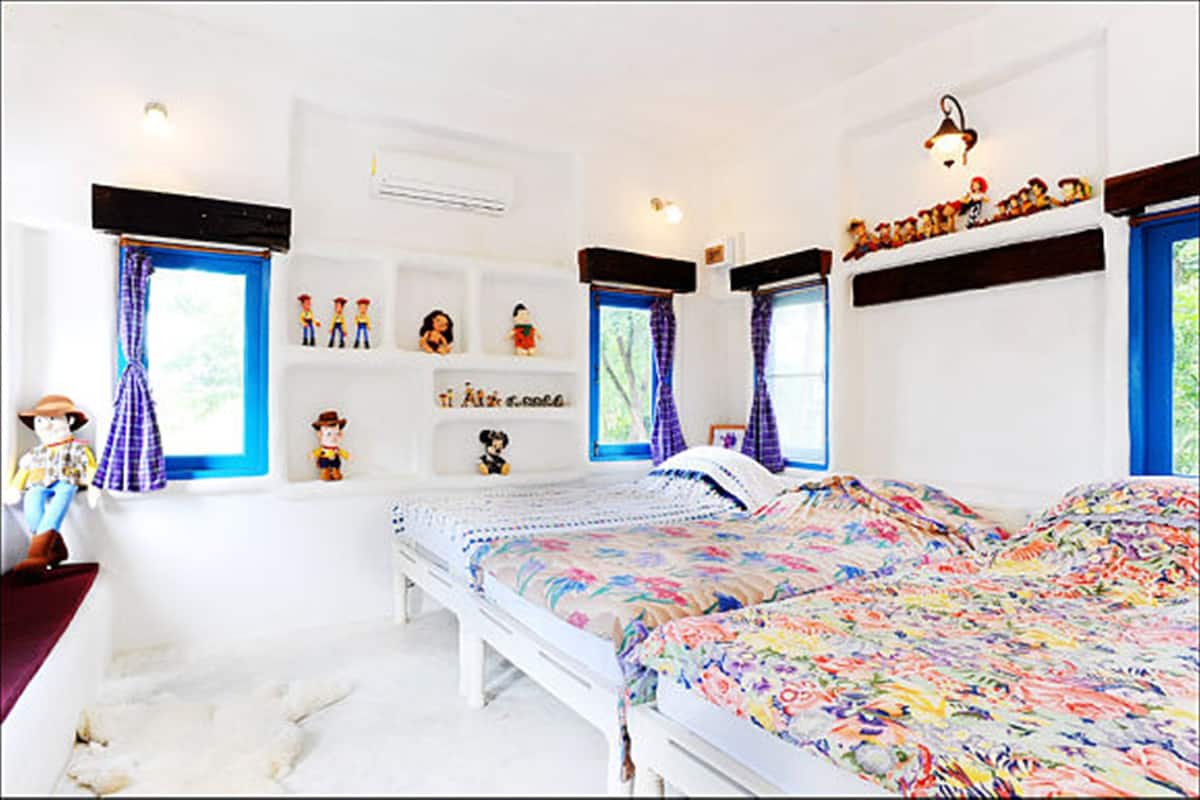 A bedroom with two beds, a dresser, and a window with curtains.