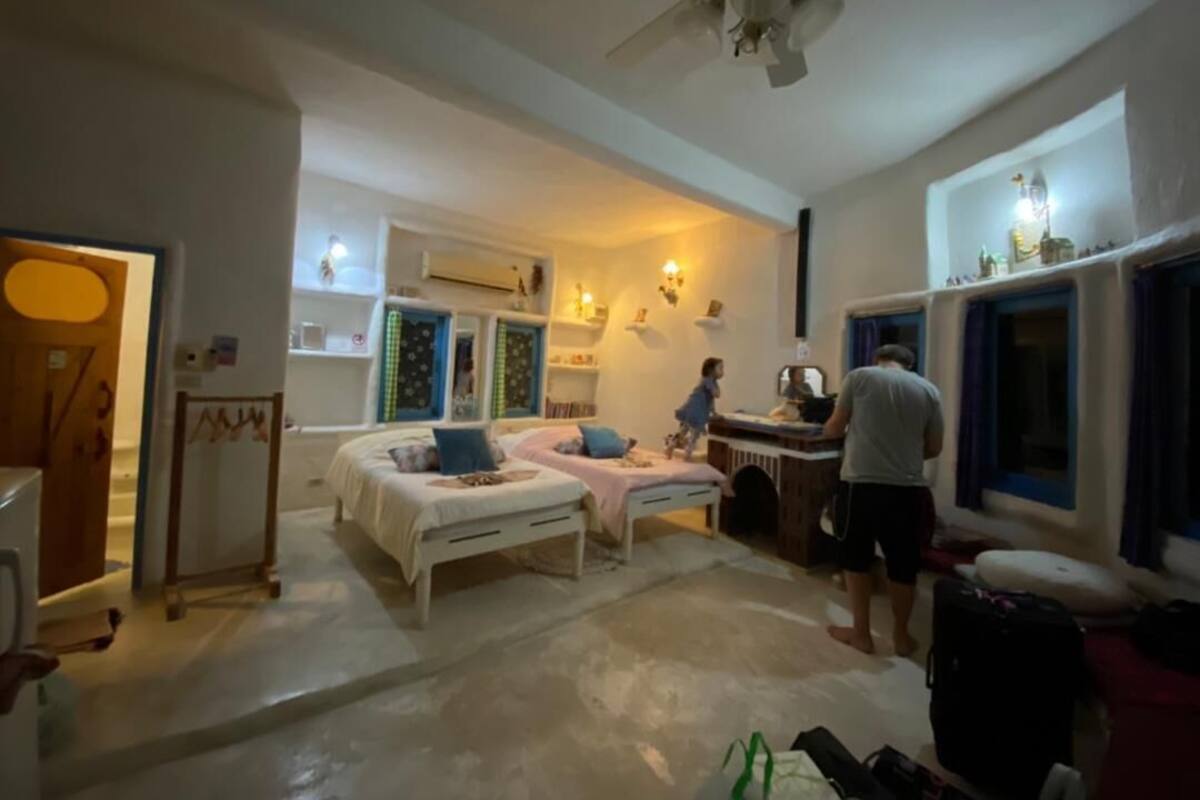 A bedroom with two beds, a desk, and a ceiling fan.