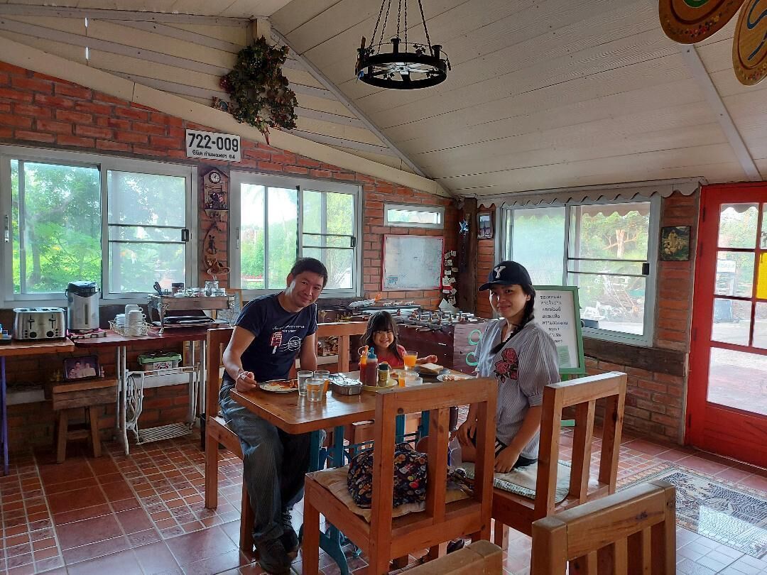 Un café rústico con paredes de ladrillo, ventanas amplias y mobiliario de madera.