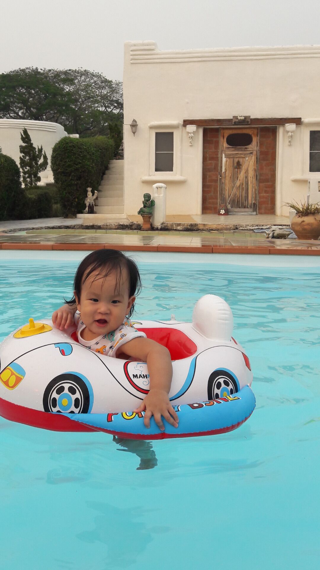 Uma criança em uma piscina com um brinquedo inflável colorido.