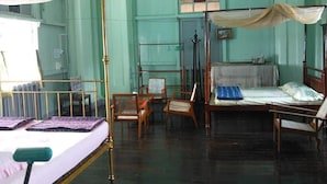 Una habitación con una cama con dosel, una silla de madera, una mesita y un ventanal con vistas al exterior.