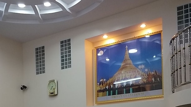Un vestíbulo con un gran reloj de pared, una mesa de recepción y un área de descanso con sillas y una mesa de madera.